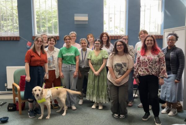 Group of attendees at Chloe Tear's talk. Chloe can be seen at the far left with Dezzie, her guide dog