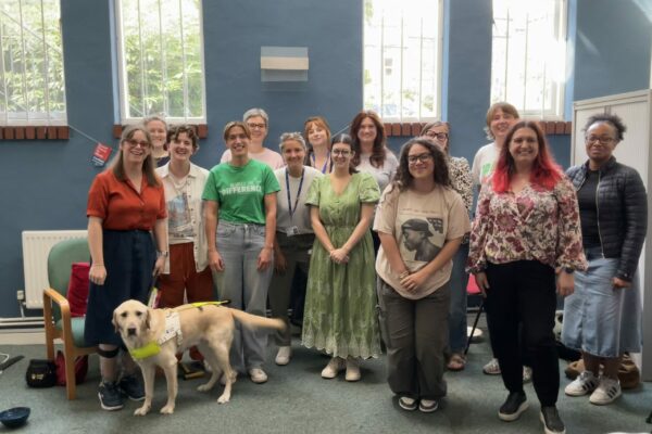 Group of attendees at Chloe Tear's talk. Chloe can be seen at the far left with Dezzie, her guide dog